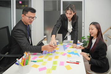 Young happy asian business man and woman work together. Creative team brainstorm meeting. Businesspeople colleague partnership or office coworker teamwork concept