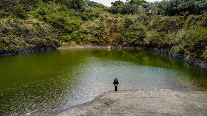 Solitary Woman Standing by Volcanic Lagoon Surrounded by Lush Forest in Costa Rica