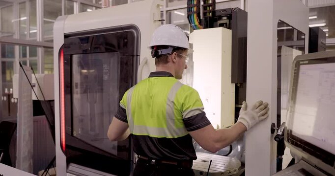 male technician in safety gear operates industrial machine touchscreen panel for electrical system control during smart factory maintenance training session under industry40 automation curriculum