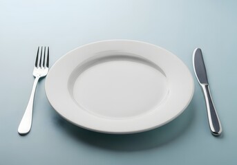 Simple table setting with white plate fork and knife on blue background