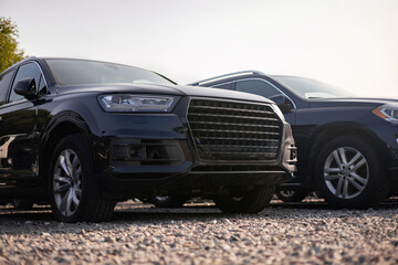 Naklejka premium Two black SUVs parked outdoors on a gravel surface, showcasing modern car design.