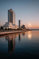 Calm waterfront cityscape at dawn, reflecting in still water