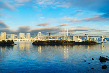Naklejka premium Skyline of Tokyo Rainbow Bridge in morning sunlight under blue sky with cloud