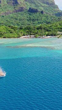 Bora Bora Island, French Polynesia. Vertical Drone Shot of Cargo Barge Boat Sailing in Lagoon Away From Green Coastline