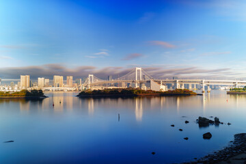 Skyline of Tokyo Rainbow Bridge in morning sunlight under blue sky with cloud