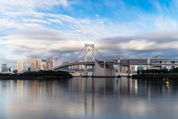 Skyline of Tokyo Rainbow Bridge in morning sunlight under blue sky with cloud