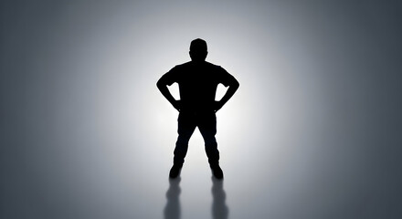 Silhouette of a confident man standing with hands on hips in a powerful pose against a bright backlight creating a dramatic and inspiring atmosphere for leadership and strength themes