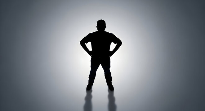 Silhouette of a confident man standing with hands on hips in a powerful pose against a bright backlight creating a dramatic and inspiring atmosphere for leadership and strength themes - Powered by Adobe