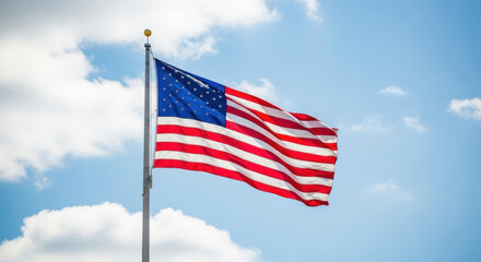 Obraz premium The american flag waves proudly against a bright blue sky with fluffy white clouds on a sunny day