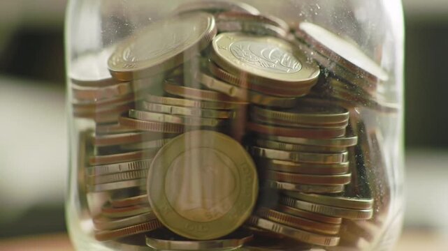 Clear Glass Jar Filled with Assorted Euro Coins in Warm Dim Lighting