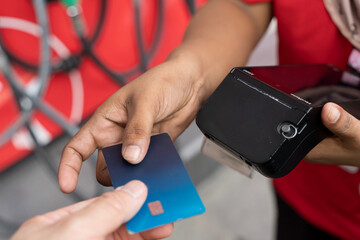 Hand holding credit card making payment with portable POS terminal during transaction at service station