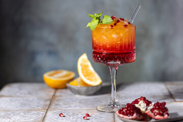 Sunrise cocktail in a tall glass with a straw, pomegranate, orange, crushed ice