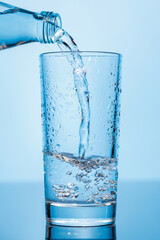 Crystal clear water being poured into a transparent glass, creating refreshing ripples and bubbles