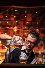 Bartender is pouring whiskey into a glass in a restaurant