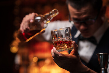 Bartender is pouring whiskey into a glass in a restaurant