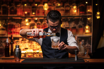 Bartender is pouring whiskey into a glass in a restaurant