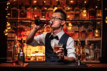 Bartender pours himself a glass of whiskey in a restaurant.