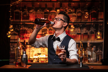 Bartender pours himself a glass of whiskey in a restaurant.