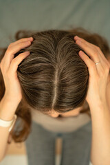 Fototapeta premium Close-up view from above of a woman touching her scalp and showing gray roots. Beauty in aging, self-acceptance, and gentle hair care. Natural transformation, soft light, healthy texture.