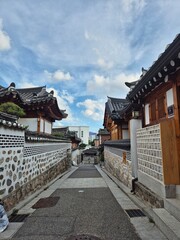 Naklejka premium Traditional Korean Hanok Alleyway Leading to the City 