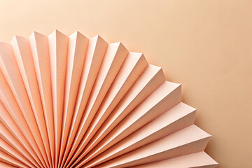 Close up of a pleated paper fan in a soft peach color against a neutral background