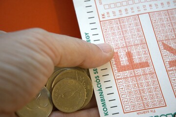 Hungarian Lottery Ticket and Forint Coins Close-Up with hand