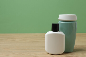 White bottles of toiletries on a wooden table with a green background