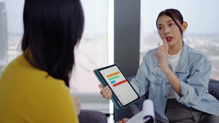 In a modern office, Asian businesswoman presents data summary charts on a tablet to her colleagues, financial report analysis teamwork strategy planning corporate success, marketing, data analytics - Powered by Adobe