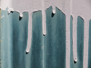 Hardened white paint flowing down against a green rustic walls