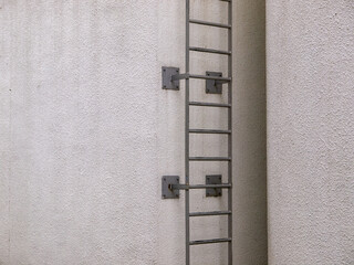 Grey steel ladder mounted on a white wall.