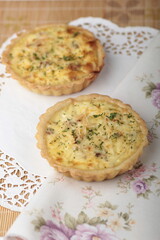 Two freshly baked, individual-sized quiches with a golden crust and a savory filling, garnished with herbs