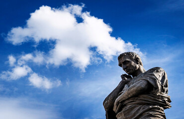 Contemplative Bronze Statue Against Blue Sky
