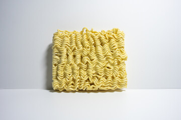 A close-up shot of a block of uncooked instant noodles, showing its distinctive wavy texture and shape, ready to be prepared.
