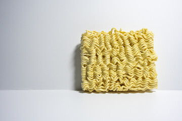 A close-up shot of a block of uncooked instant noodles, showing its distinctive wavy texture and shape, ready to be prepared.