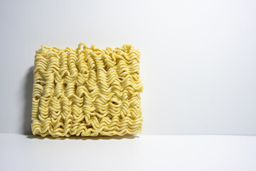 A close-up shot of a block of uncooked instant noodles, showing its distinctive wavy texture and shape, ready to be prepared.