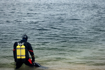 Diver in a dry suit prepares to dive into cold water, extreme diving