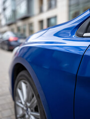 Close-up of a shiny blue car parked on a city street.