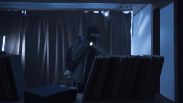 Thief in black balaclava with flashlight making housebreak. Robber criminal entering a house for money stealing at night