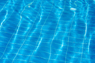 Clear turquoise water fills the swimming pool with sunlight creating shimmering reflections....