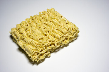 A close-up shot of a block of uncooked instant noodles, showing its distinctive wavy texture and shape, ready to be prepared.