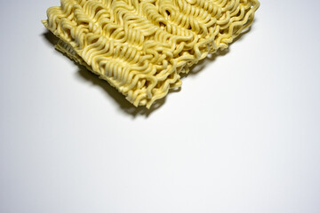 A close-up shot of a block of uncooked instant noodles, showing its distinctive wavy texture and shape, ready to be prepared.