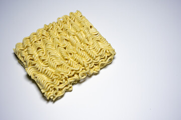 A close-up shot of a block of uncooked instant noodles, showing its distinctive wavy texture and shape, ready to be prepared.