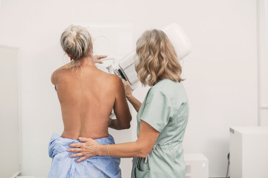 50-year-old woman undergoes mammography procedure on special medical equipment mammograph with the help of assistant in modern clinic. Regular medical examination, screening for breast cancer