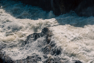streams of clear waterfall water and stone banks of a mountain river