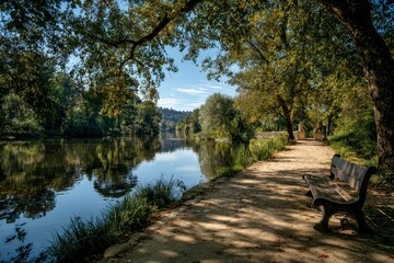 Fototapeta premium Relaxing walk along the serene Monrepos Park promenade with lush trees and calm waters during a sunny day