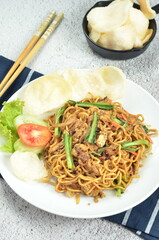 Indonesian fried noodles with egg, chicken, mustard greens, and crackers