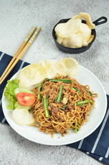 Indonesian fried noodles with egg, chicken, mustard greens, and crackers