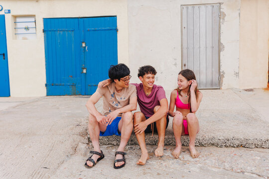 A dad sits with two children by shuttered cabanas at beach