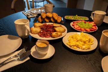 A table with a variety of food and drinks, including coffee, croissants, and fruit