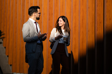 Business people talking and gesturing during coffee break outside office